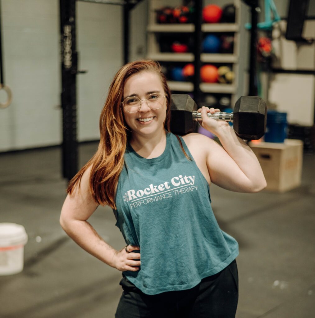 rocket city performance therapy owner smiling and holding a dumbell